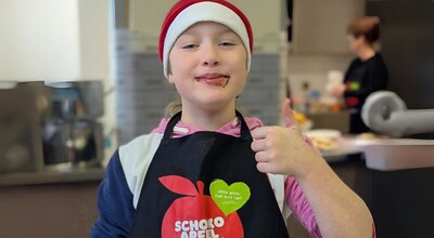 Schülerin der Grundschule Wolmirstedt mit Schokomund, Weihnachtsmütze und Küchenschürze 